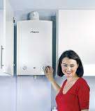 Woman standing next to a wall-mounted combi boiler – choosing the right boiler type.